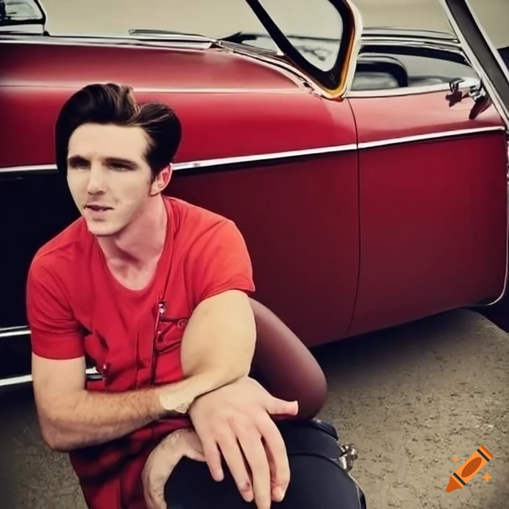 Drake bell posing next to a classic red car