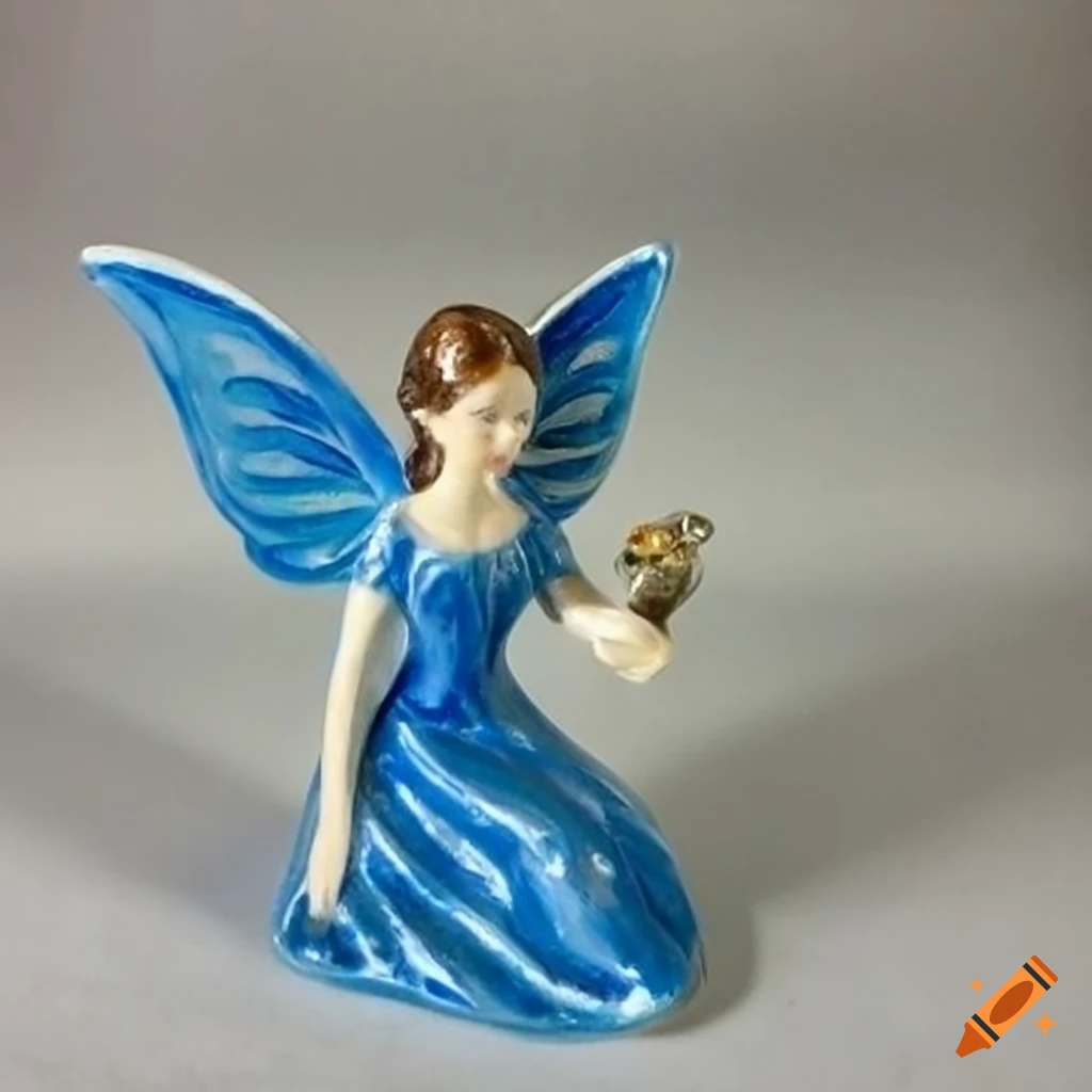 Beautiful fairy in a blue dress holding a small bird, ceramic figurine